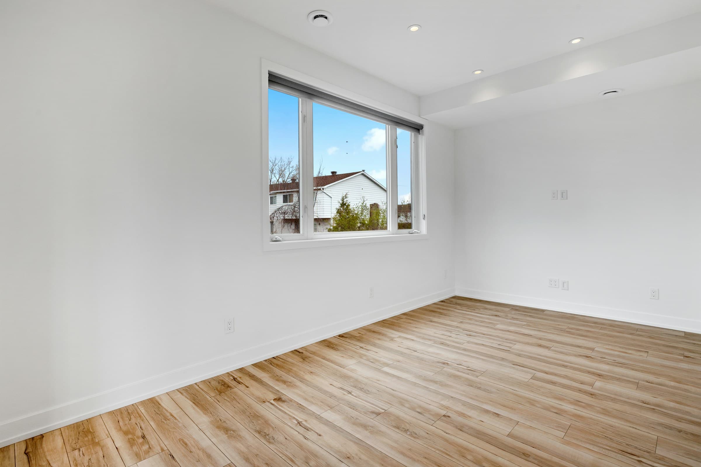 An empty room with sunlight on hardwood floors.